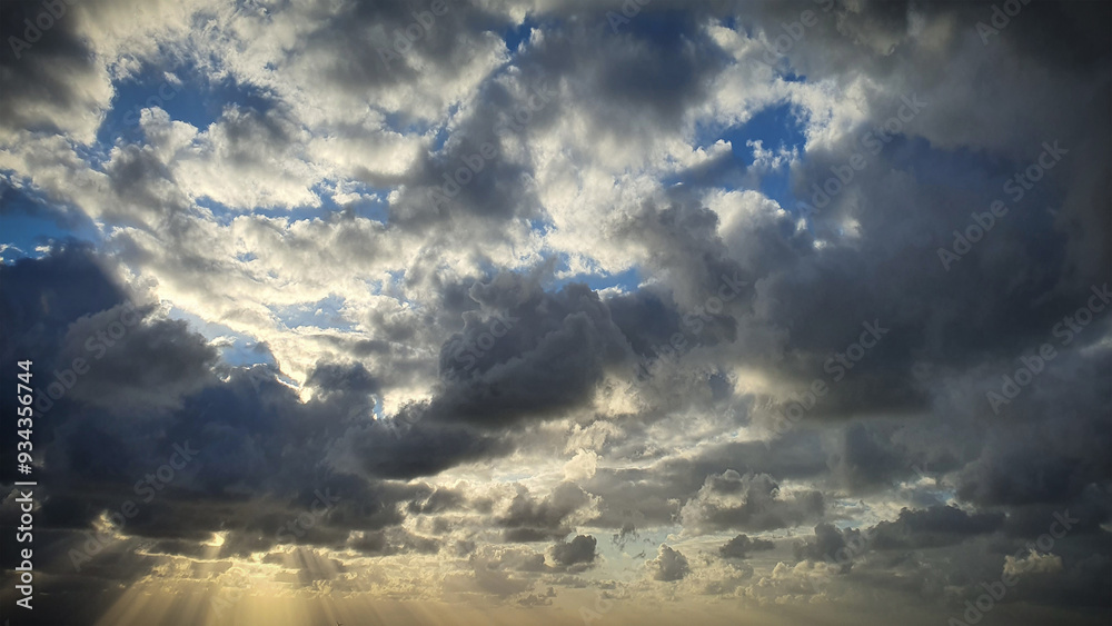 Fototapeta premium A stunning natural background showcasing dramatic clouds illuminated by the setting sun, with blue sky peeking through. Ideal for 4K wallpapers, banners, and natural-themed backdrops
