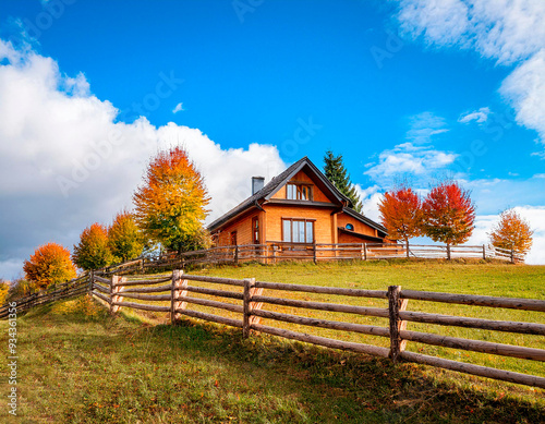 Casa campestre en la colina con cercado de madera y árboles de colores. photo