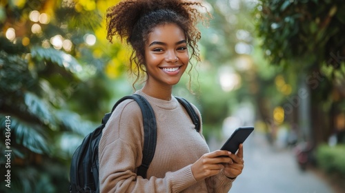 Young woman smiling and using smartphone in a lush urban park during daytime