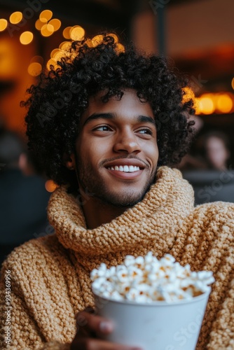 Cozy night in with a man enjoying popcorn while wrapped in a blanket at home