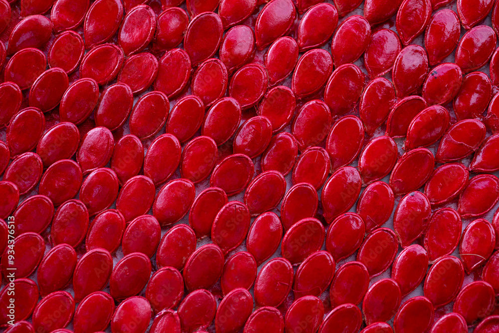 Obraz premium Pumpkin seeds arranged evenly and painted red. Background. Texture.