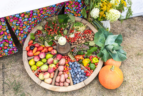 Colorful sellection of fruits apples, berries, nuts and vegetables , cucumber, cabbage, carrots, potatoes, in an old wooden carriage wheel. photo