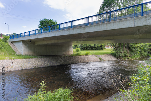 Reinforced concrete road bridge over the river. Close-up during sunny day in summer. Aerial view on a bridge across a small river. Canal or ditch with green grass meadow, Underneath of classic style 