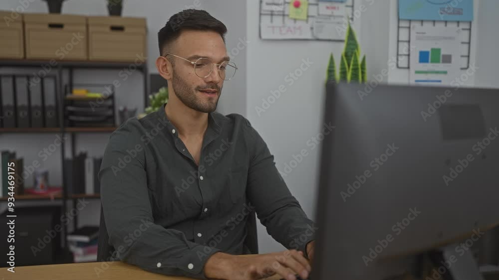 Young hispanic man working at a desktop computer in a modern office room looks stressed out with his hands on his face Young hispanic man working at a desktop computer in a modern office room looks stressed out with his hands on his face