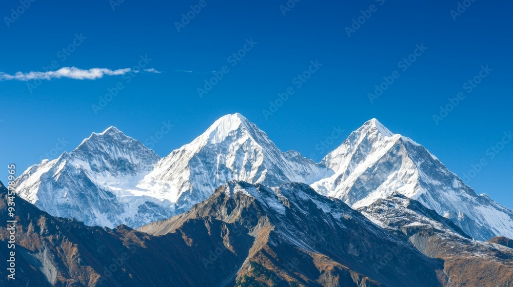 Fototapeta premium Majestic mountain range with snow-capped peaks and clear blue sky above. Majestic Mountain Range