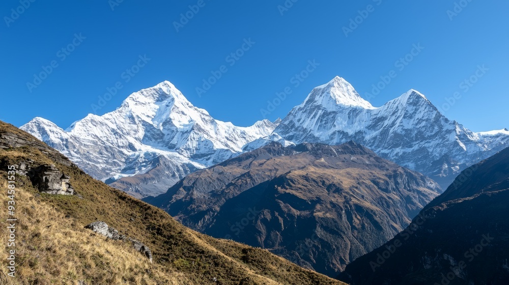 Fototapeta premium Majestic mountain range with snow-capped peaks and clear blue sky above. Majestic Mountain Range
