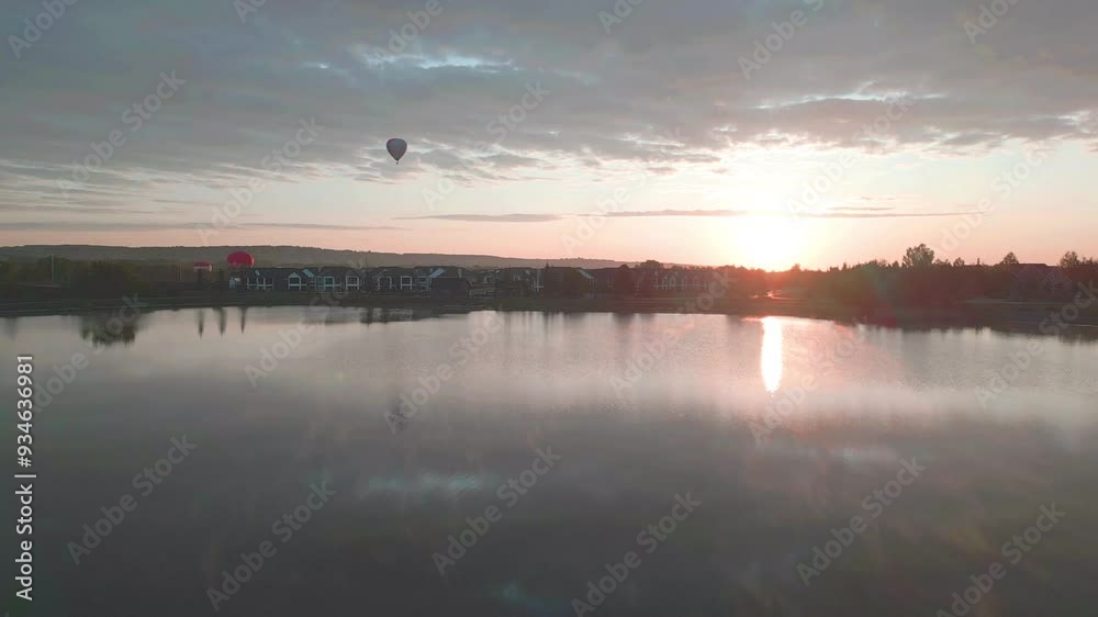 The view from a boat of multiple hot air balloons flying just above the pond waves at sunrise sky. beautiful reflection on water surface. An Aerial View of Multiple Hot Air Balloons Floating 