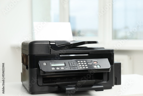 Modern printer with paper on white table in office