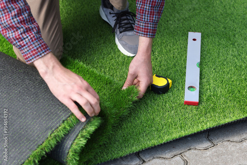 Man installing artificial turf outdoors, closeup view