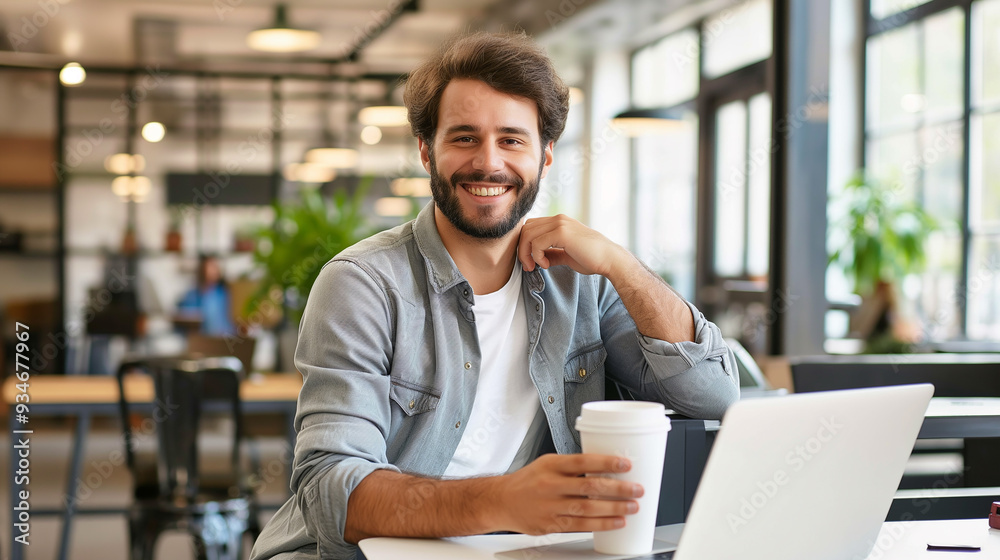 Portrait of smiling young male businessman working on laptop sitting in modern office drinking coffee in recyclable cup, happy businessman Portrait of smiling young male businessman working on laptop sitting in modern office drinking coffee in recyclable cup, happy businessman