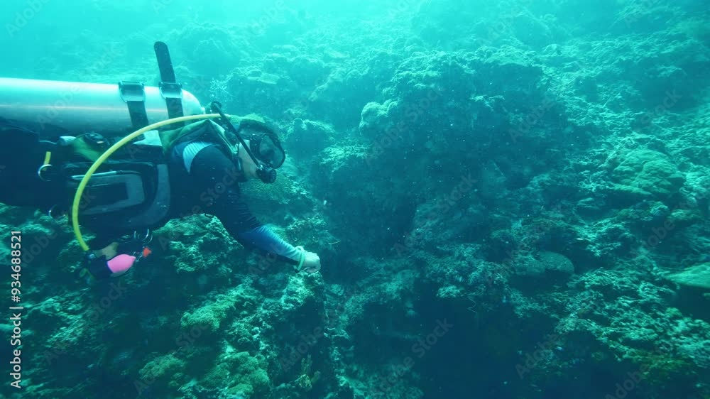 Skilled diver holds action camera recording ocean floor