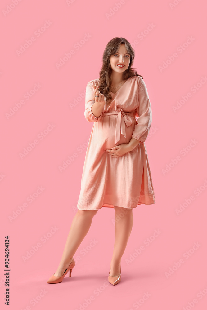 Young pregnant woman showing heart gesture on pink background. Valentine's Day celebration Young pregnant woman showing heart gesture on pink background. Valentine's Day celebration