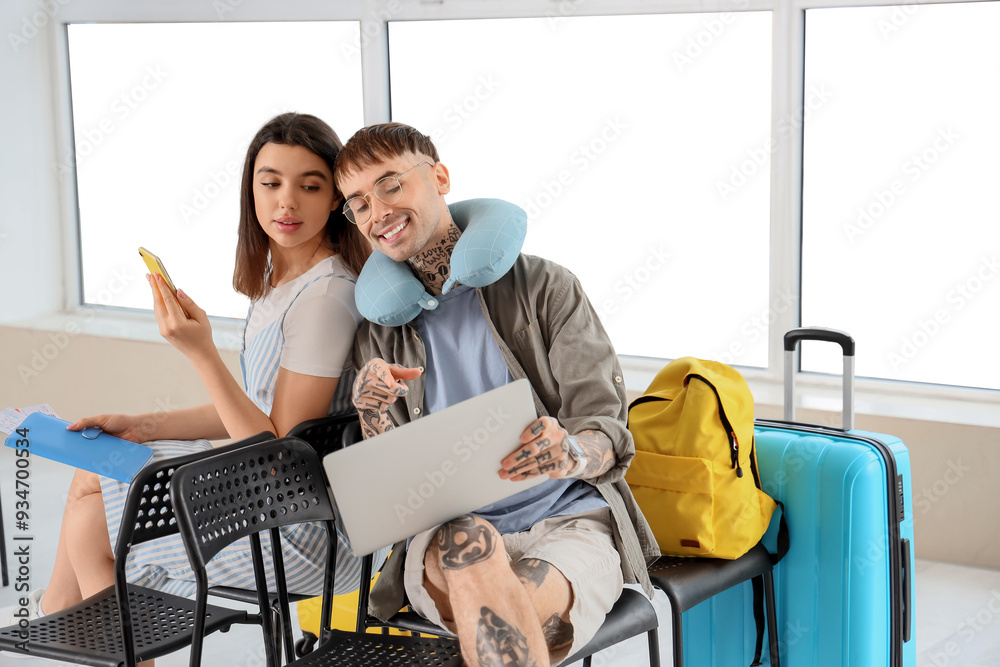 Couple of tourists using laptop at airport Couple of tourists using laptop at airport