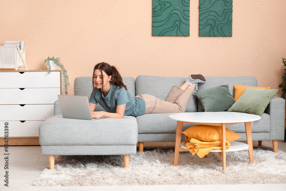 Young woman chatting with laptop and lying on comfortable sofa in living room Young woman chatting with laptop and lying on comfortable sofa in living room