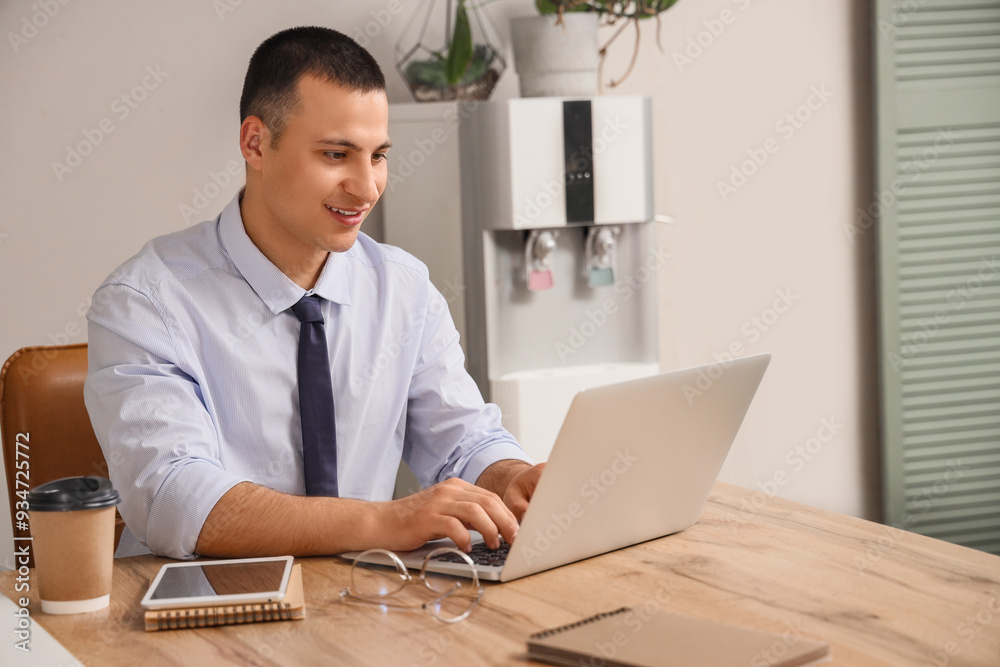 Fototapeta premium Handsome businessman working with laptop at desk in office