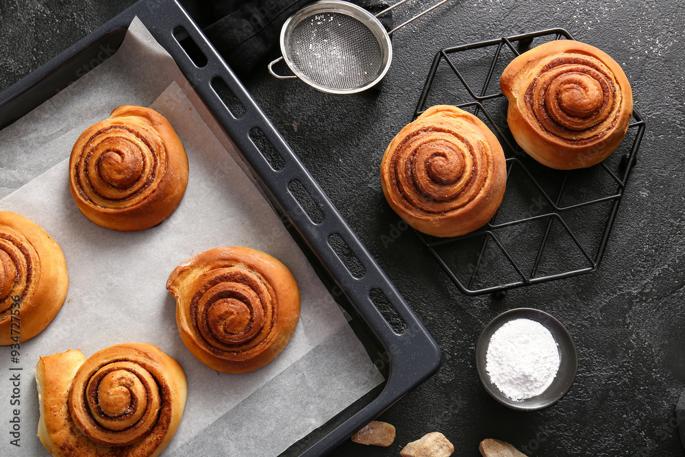 Baking dish and stand with sweet cinnamon rolls on black background Baking dish and stand with sweet cinnamon rolls on black background