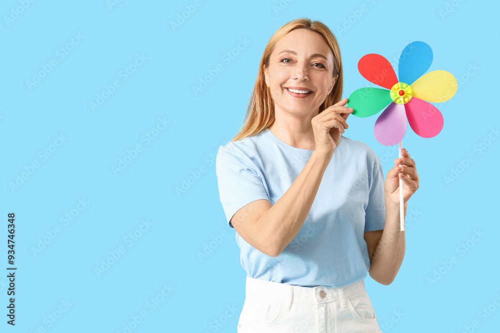Mature woman with toy windmill on blue background Mature woman with toy windmill on blue background