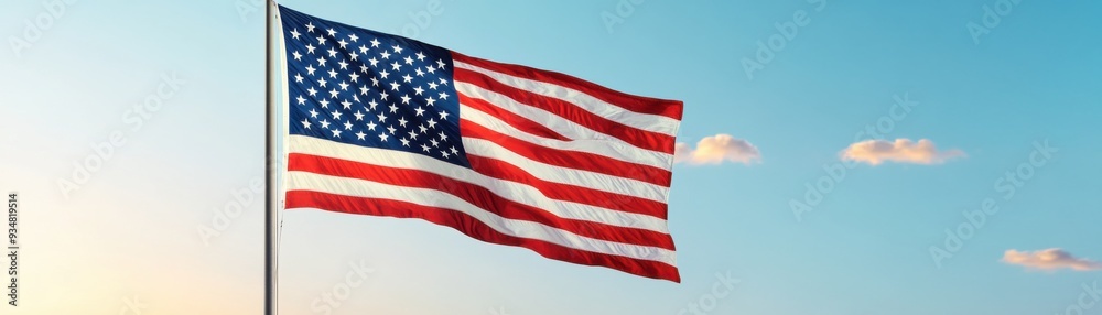 Obraz premium The American flag waves proudly against a clear blue sky, symbolizing freedom and national pride.