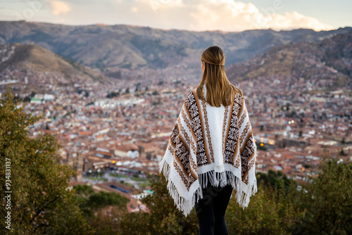 
Young woman wearing a traditional Peruvian poncho looking at the city from a well-known viewpoint in Cusco Peru