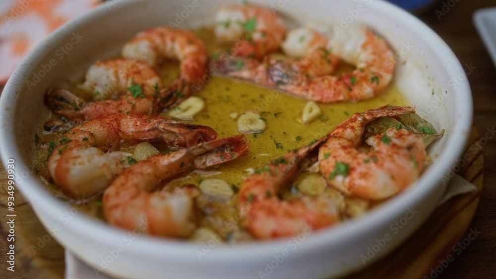 Grilled shrimp served in garlic butter with parsley garnish in a white bowl at a restaurant table shows the delicious detail of the seafood dish in a close up Grilled shrimp served in garlic butter with parsley garnish in a white bowl at a restaurant table shows the delicious detail of the seafood dish in a close up