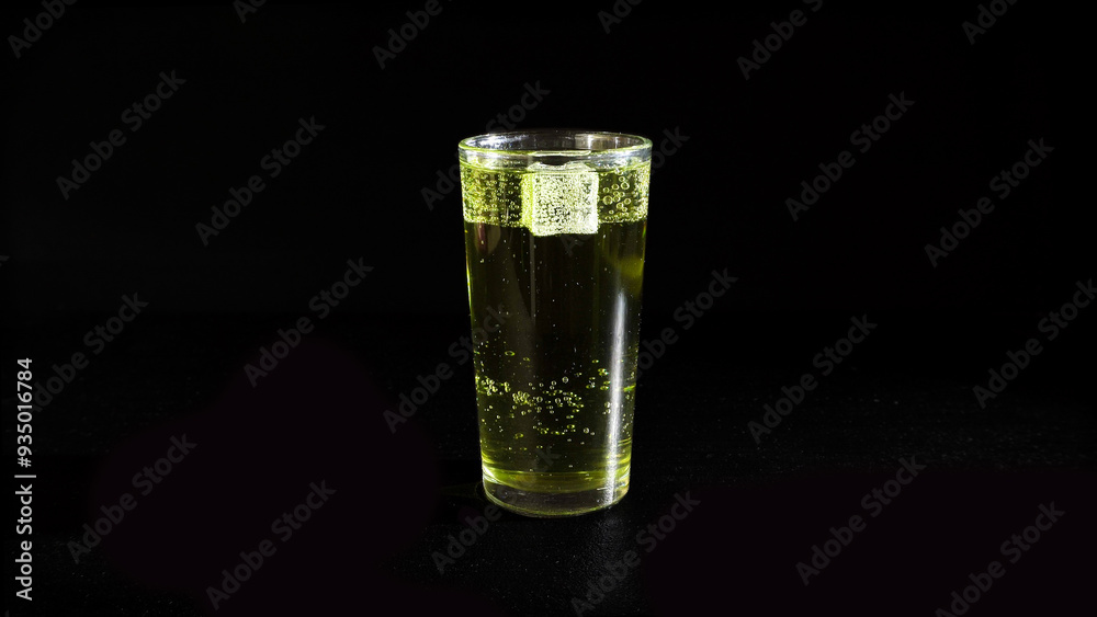 Lemonade with Rising Bubbles and Ice Cubes in Glass on a Black Background Lemonade with Rising Bubbles and Ice Cubes in Glass on a Black Background