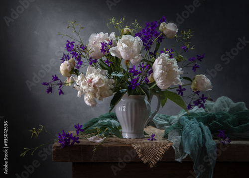 Still life with white peonies and delphinium on a dark background