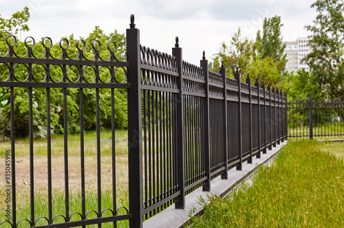 Metal fence in the city park. Decorative black iron guardrail for protection, close up