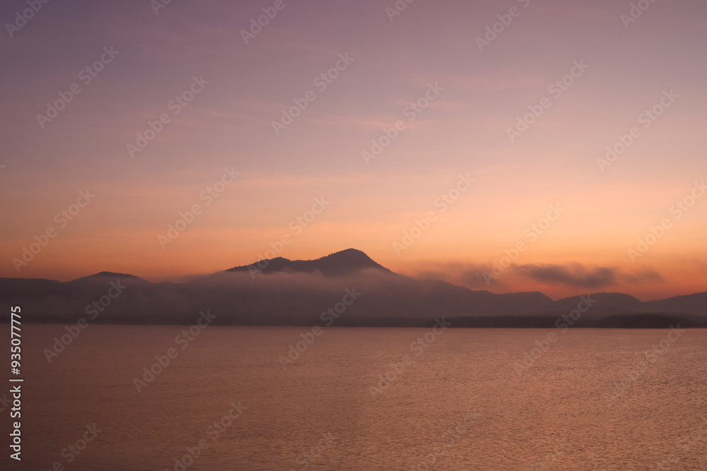 Photographs of intricate mountain ranges at sunset The golden rays of the sun shone on the surface of the water. The shadow of the mountain reflected on the surface of the water. Gives a feeling of r Photographs of intricate mountain ranges at sunset The golden rays of the sun shone on the surface of the water. The shadow of the mountain reflected on the surface of the water. Gives a feeling of r