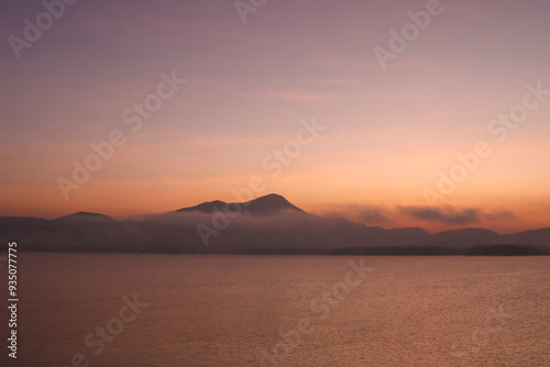 Photographs of intricate mountain ranges at sunset The golden rays of the sun shone on the surface of the water. The shadow of the mountain reflected on the surface of the water. Gives a feeling of r