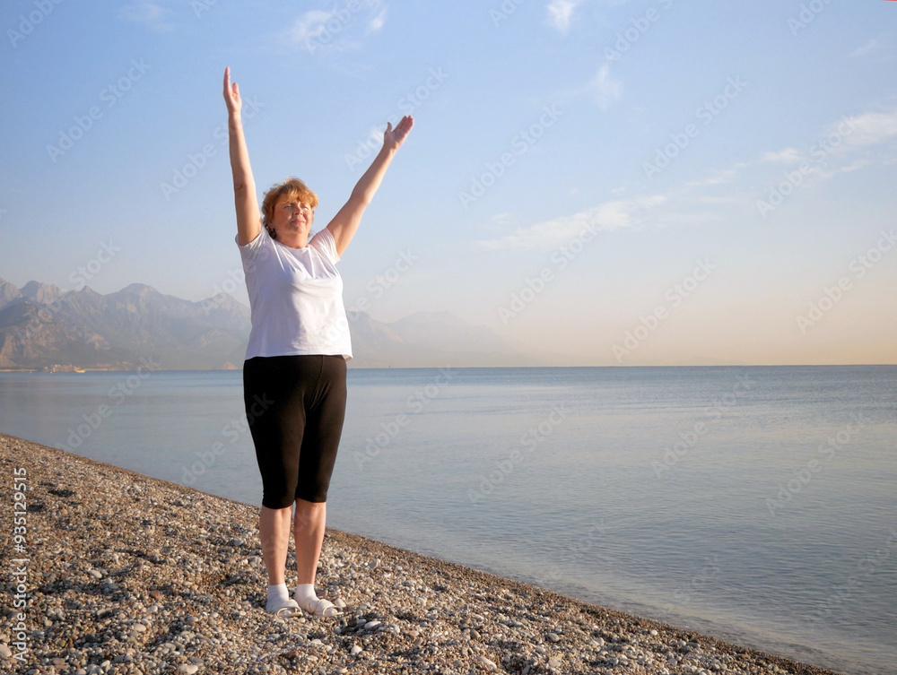 Middle aged woman doing yoga exercise on sea beach in the summer morning Middle aged woman doing yoga exercise on sea beach in the summer morning