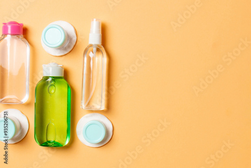 Group of small bottles for travelling on colored background. Copy space for your ideas. Flat lay composition of cosmetic products. Top view of cream containers with cotton pads