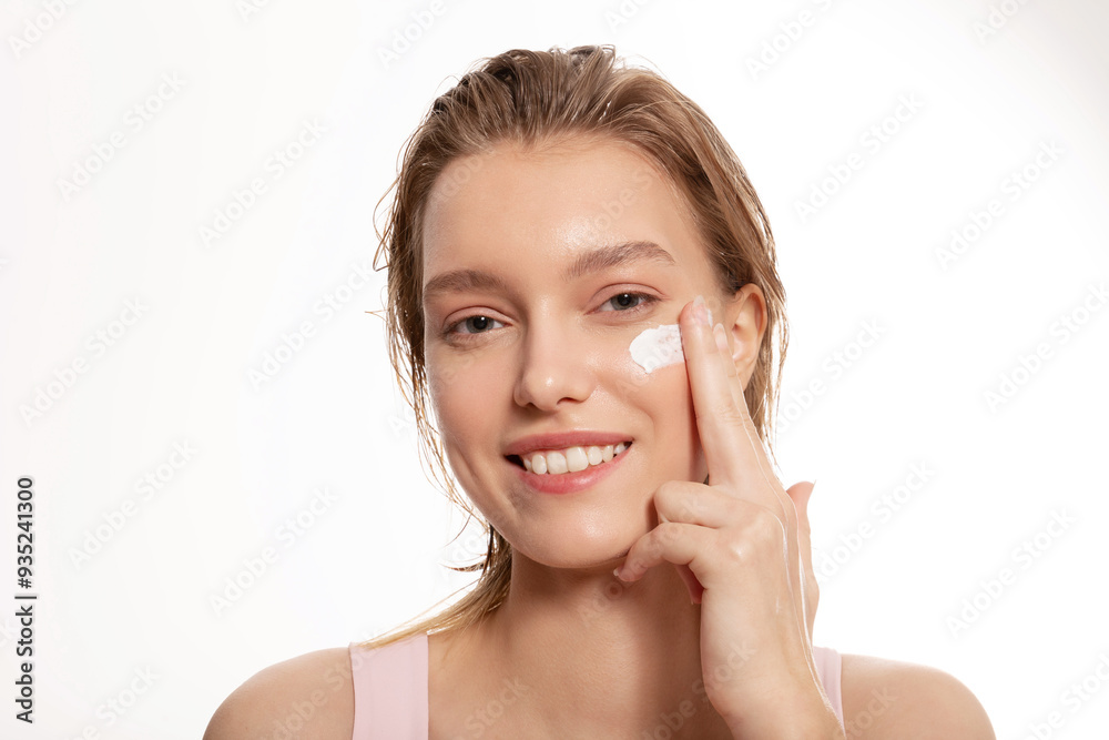 Happy woman applying moisturizer cream to her face and smiling Happy woman applying moisturizer cream to her face and smiling
