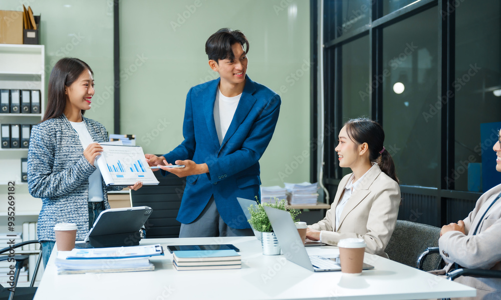 Obraz premium In a boardroom, an Asian team meets at a desk, presenting financial terms and strategies. Executives and employees collaborate, sharing ideas and work guidelines for success during an annual meeting.