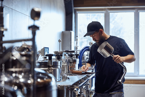 Standing in brewery, technologist taking notes during checking brewing process and equipment. Science and craft in beer production. Concept of beer, brewery, manufacture, quality control