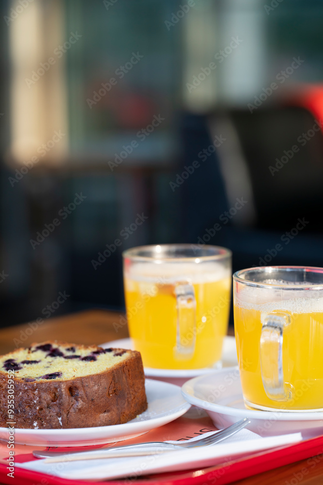 Orange-ginger tea in clear mugs with currant muffin on a table in a cafe. High quality photo Orange-ginger tea in clear mugs with currant muffin on a table in a cafe. High quality photo