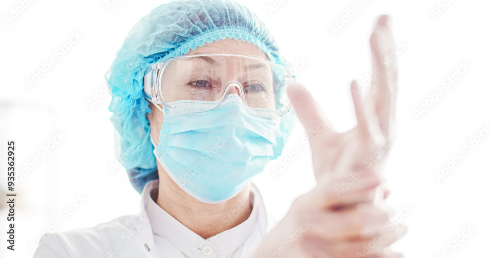 Close up portrait of female puts on specialized clothes. Woman wearing protective glasses with medical cap and mask. Female doctor puts on medical gloves. Close up portrait of female puts on specialized clothes. Woman wearing protective glasses with medical cap and mask. Female doctor puts on medical gloves.