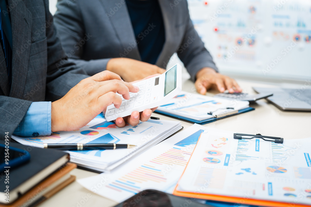 close-up of two professionals' hands meeting at a desk, discussing business strategies over a digital tablet and laptop. teamwork, planning, and communication in a corporate office setting.