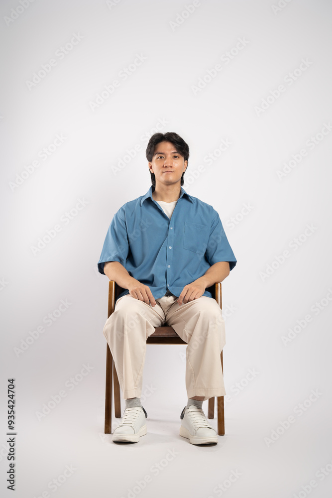Portrait of young Asian business man sitting in chair, isolated on white background