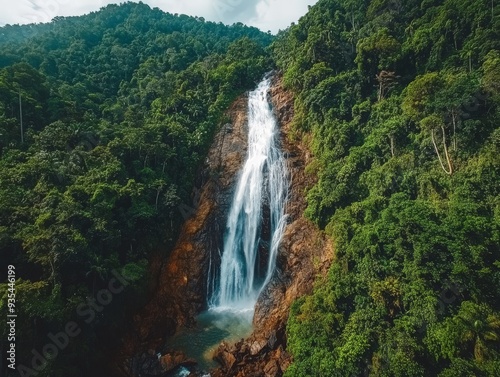 Aerial View of Waterfall Plunging Through Lush Green Forest.