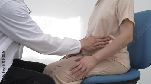Asian female doctor listens to belly of pregnant mother during a prenatal exam in clinic. doctor provides caring advice, ensuring the health and happiness of the expecting mother and baby.