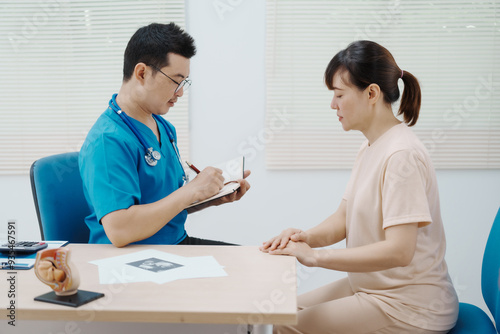 Asian female doctor listens to belly of pregnant mother during a prenatal exam in clinic. doctor provides caring advice, ensuring the health and happiness of the expecting mother and baby.