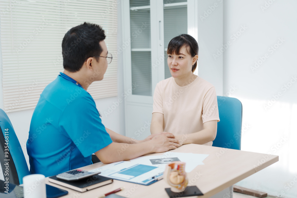 Fototapeta premium Asian female doctor listens to belly of pregnant mother during a prenatal exam in clinic. doctor provides caring advice, ensuring the health and happiness of the expecting mother and baby.