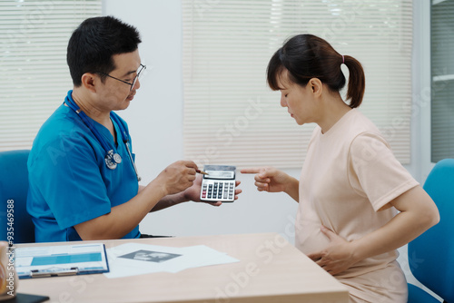 Asian female doctor listens to belly of pregnant mother during a prenatal exam in clinic. doctor provides caring advice, ensuring the health and happiness of the expecting mother and baby.