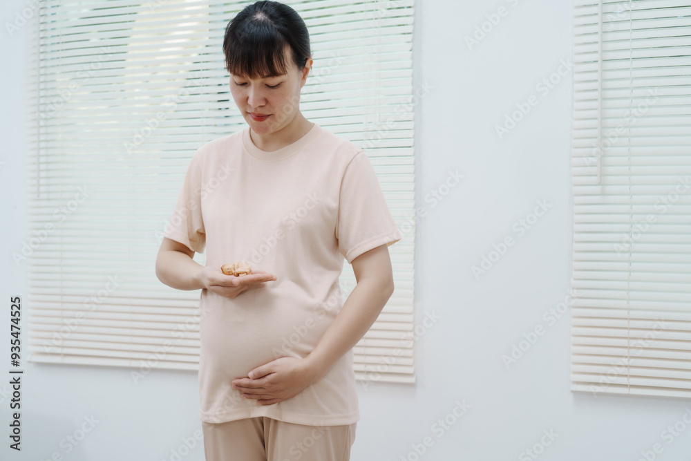 A side view studio portrait of a smiling young Asian pregnant woman gently touching her abdomen. The cut-out, white background highlights her joy, anticipation, and love for the new life she carries. A side view studio portrait of a smiling young Asian pregnant woman gently touching her abdomen. The cut-out, white background highlights her joy, anticipation, and love for the new life she carries.
