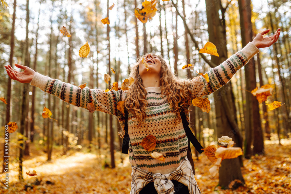 Woman enjoying a joyful moment in a sunny autumn forest surrounded by colorful leaves and towering trees Woman enjoying a joyful moment in a sunny autumn forest surrounded by colorful leaves and towering trees