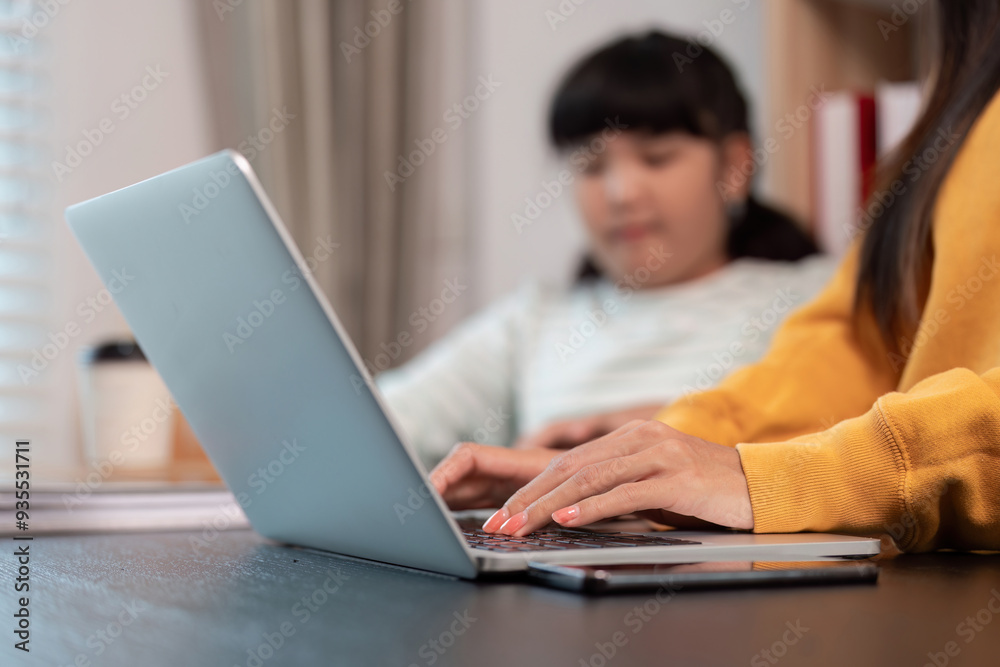 Focused hands typing on laptop with daughter watching Focused hands typing on laptop with daughter watching