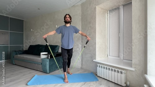 Sportsman performing a lateral raise with a resistance band in an apartment, showcasing effective home workout techniques