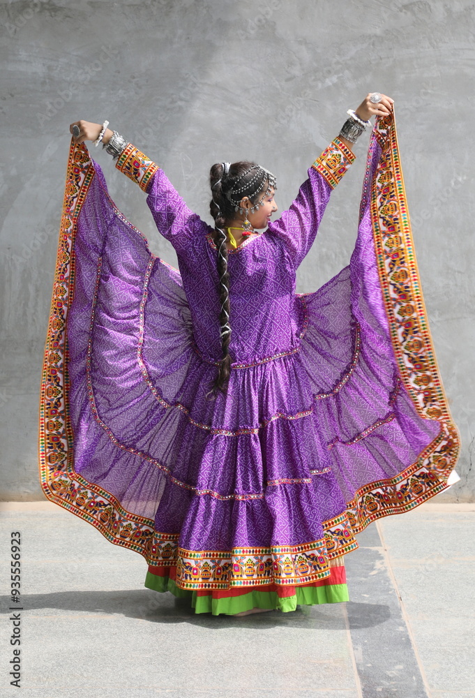 Naklejka premium woman is wearing ruffled shrug of purple bandhani print. full flare banjara shrug on chaniya choli for garba in navratri. Traditional gujarati outfit with long braid. Unique navratri look and outfit. 