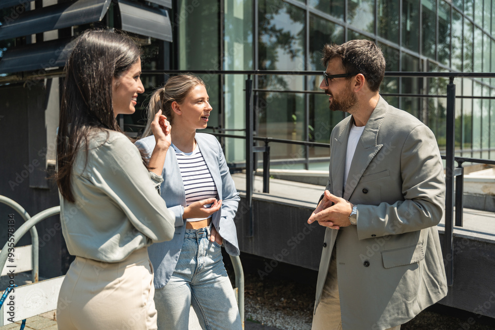 Teamwork skills exchanging. Group of young business people working on ideas outside of office building. Businessman and businesswoman discussing and preparing for new opportunities at work. Teamwork skills exchanging. Group of young business people working on ideas outside of office building. Businessman and businesswoman discussing and preparing for new opportunities at work.
