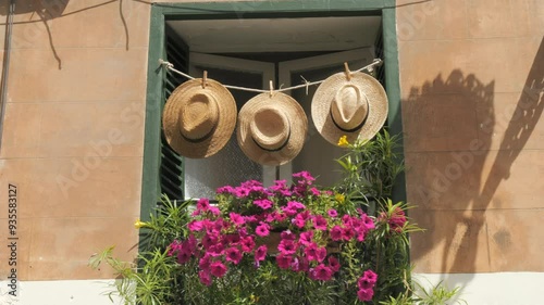 Spanish vibe. Decorated window with straw hats and flowers on a summer day